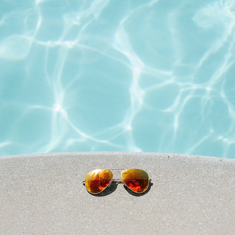 Sonnenbrille am Beckenrand eines Pools  