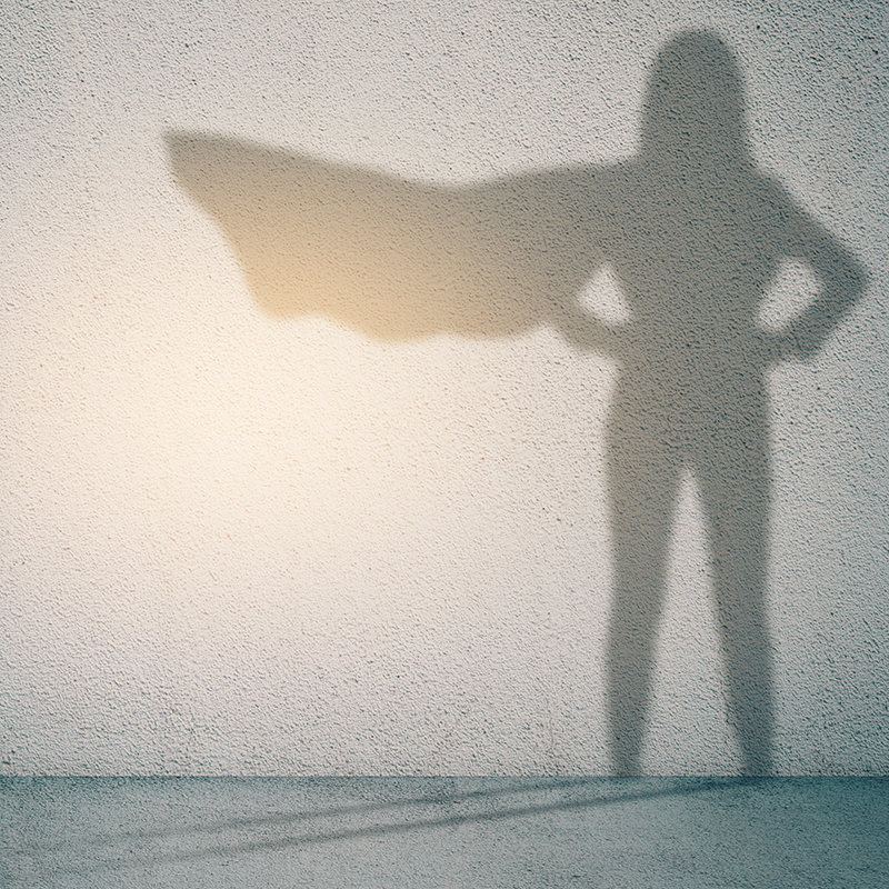 Schatten einer Frau mit wehendem Superheldenumhang  