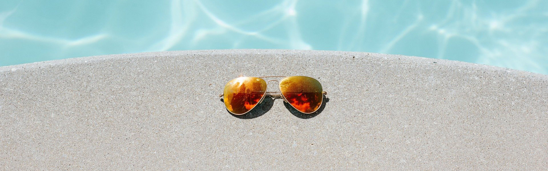 Sonnenbrille am Beckenrand eines Pools