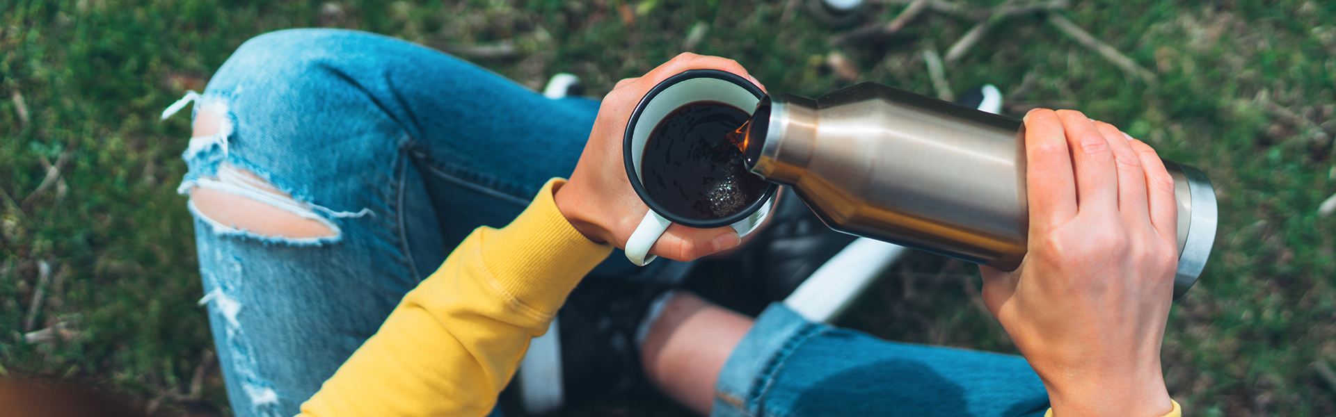 Mädchen gießt Kaffee aus Thermosflasche in Becher